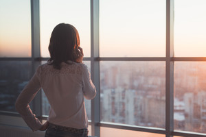 Woman looking out window on phone